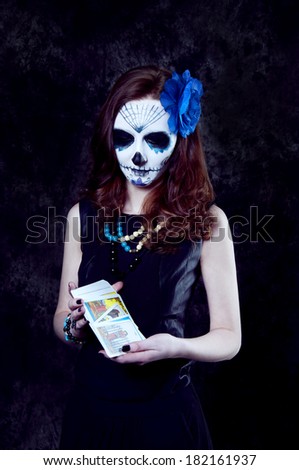 Woman witch with scary makeup with tarot cards preparing for a reading