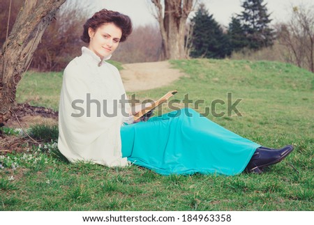 Young caucasian woman in retro outfit reading in the garden