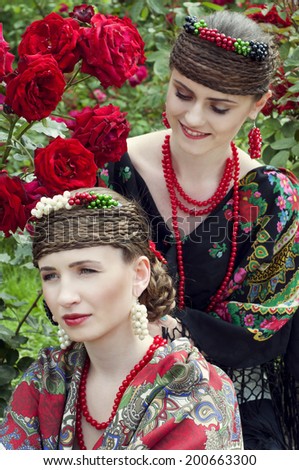 Two caucasian slavonic women sitting in the field of red roses
