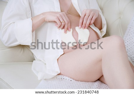 Pregnant woman holding tiny baby socks on her belly
