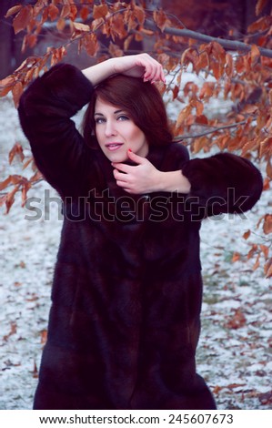 Outdoor winter portrait of beautiful smiling redheaded woman in fur coat