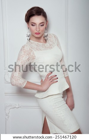 Studio portrait of elegant woman in white cocktail dress with expensive earrings