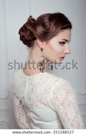 Studio portrait of elegant woman in white cocktail dress with expensive earrings