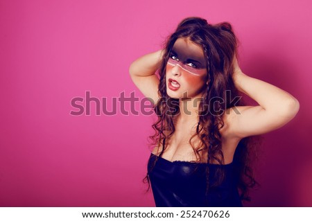 young woman with tribal makeup dressed in leather going wild on pink background