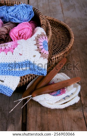 Box of pink and blue yarn and granny square blanket with crochet hooks