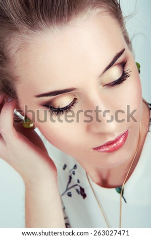 Beautiful sexy woman with natural day makeup and bright green eyes wearing green earrings