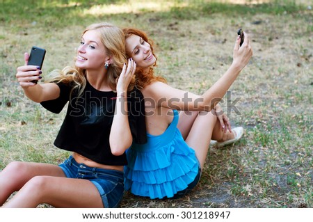 Two girlfriends taking a selfie in the park. Summer activities.