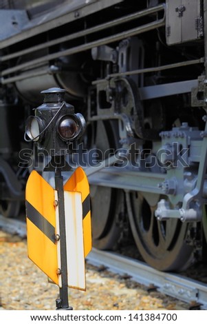 Old railroad signal in front of steam locomotive wheels/Railroad Signal and Steam Locomotive