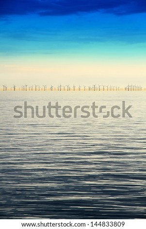 Line of wind energy mills on the coastal horizon/Offshore Wind Farm