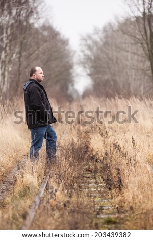 Middle aged man is walking along abandoned railway tracks/Short Break at the Way of Life