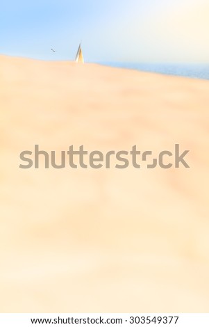 Large sand dune and sail of a boat at the sunny blue ocean horizon/Summer Day with Boat at the Sea