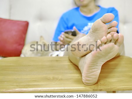 a foot relax on table between play game on smartphone