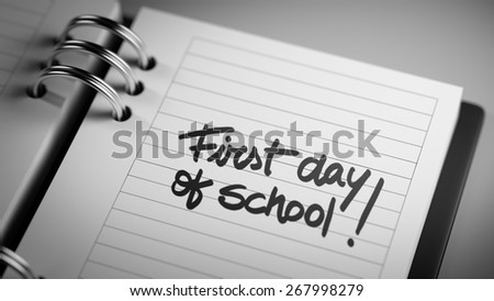 Closeup of a personal agenda marking a day of the month representing a organizing time and schedule. First day of school text note reminder concept. Words First day of school written in Black Marker.