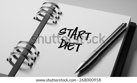 Closeup of a personal agenda with a Ballpoint pen marking a day of the month representing a schedule. Start Diet text note reminder concept. Words Start Diet written in Black Marker.