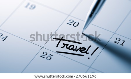 Closeup of a personal agenda setting an important date written with pen. The words Travel written on a white notebook to remind you an important appointment.