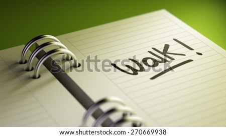 Closeup of a personal agenda setting an important date representing a time schedule. The words Walk written on a white notebook to remind you an important appointment.