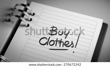 Closeup of a personal agenda setting an important date representing a time schedule. The words Buy Clothes written on a white notebook to remind you an important appointment.