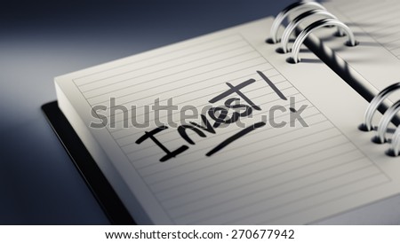 Closeup of a personal agenda setting an important date representing a time schedule. The words Invest written on a white notebook to remind you an important appointment.