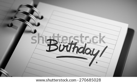 Closeup of a personal agenda setting an important date representing a time schedule. The words Birthday written on a white notebook to remind you an important appointment.
