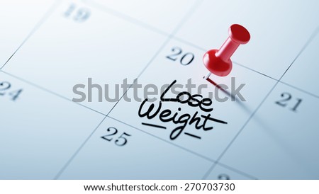 Concept image of a Calendar with a red push pin. Closeup shot of a thumbtack attached. The words Lose Weight written on a white notebook to remind you an important appointment.