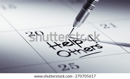 Concept image of a Calendar with a golden dart stick. The words Help Others written on a white notebook to remind you an important appointment.