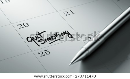 Closeup of a personal agenda setting an important date written with pen. The words Quit Smoking written on a white notebook to remind you an important appointment.
