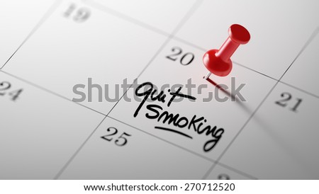 Concept image of a Calendar with a red push pin. Closeup shot of a thumbtack attached. The words Quit Smoking written on a white notebook to remind you an important appointment.
