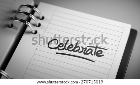 Closeup of a personal agenda setting an important date representing a time schedule. The words Celebrate written on a white notebook to remind you an important appointment.