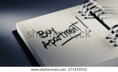 Closeup of a personal agenda setting an important date representing a time schedule. The words Buy Apartment written on a white notebook to remind you an important appointment.