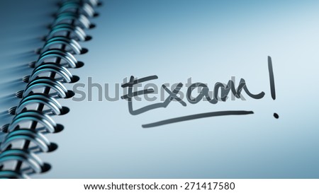 Closeup of a personal calendar setting an important date representing a time schedule. The words Exam written on a white notebook to remind you an important appointment.