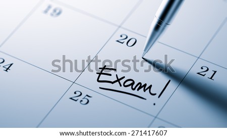 Closeup of a personal agenda setting an important date written with pen. The words Exam written on a white notebook to remind you an important appointment.