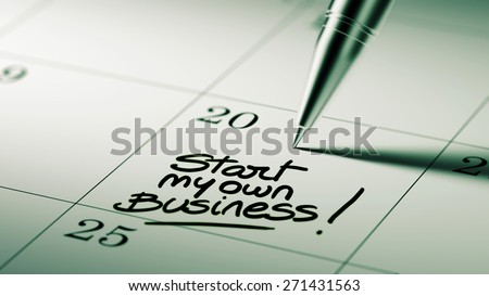 Closeup of a personal agenda setting an important date written with pen. The words Start my own Business written on a white notebook to remind you an important appointment.