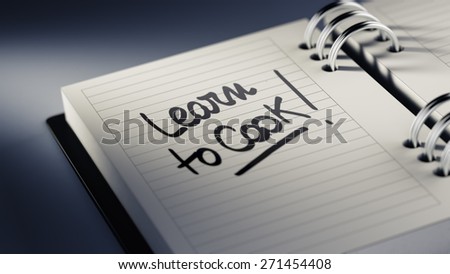 Closeup of a personal agenda setting an important date representing a time schedule. The words Learn to Cook written on a white notebook to remind you an important appointment.