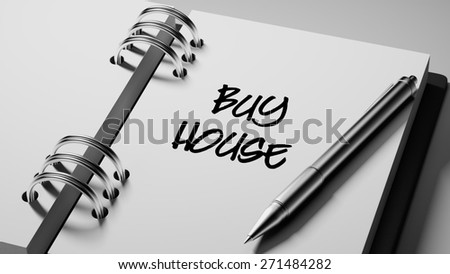 Closeup of a personal agenda setting an important date writing with pen. The words Buy House written on a white notebook to remind you an important appointment.