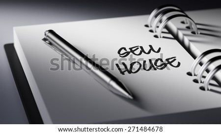 Closeup of a personal agenda setting an important date writing with pen. The words Sell House written on a white notebook to remind you an important appointment.