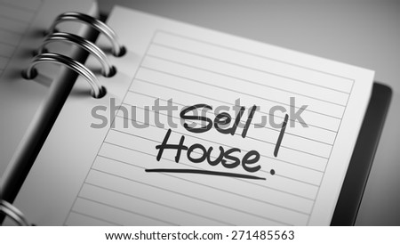 Closeup of a personal agenda setting an important date representing a time schedule. The words Sell House written on a white notebook to remind you an important appointment.