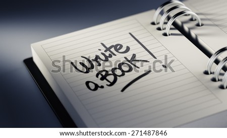 Closeup of a personal agenda setting an important date representing a time schedule. The words Write a Book written on a white notebook to remind you an important appointment.