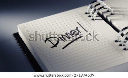 Closeup of a personal agenda setting an important date representing a time schedule. The words Dinner written on a white notebook to remind you an important appointment.