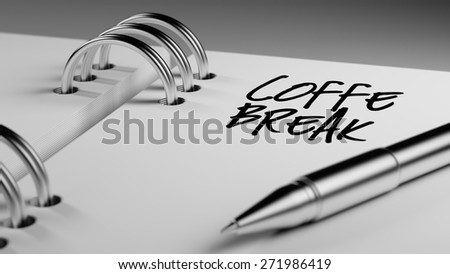 Closeup of a personal agenda setting an important date writing with pen. The words Coffee Break written on a white notebook to remind you an important appointment.
