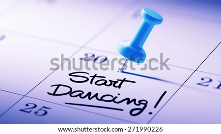 Concept image of a Calendar with a blue push pin. Closeup shot of a thumbtack attached. The words Start Dancing written on a white notebook to remind you an important appointment.