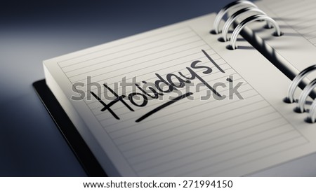 Closeup of a personal agenda setting an important date representing a time schedule. The words Holidays written on a white notebook to remind you an important appointment.