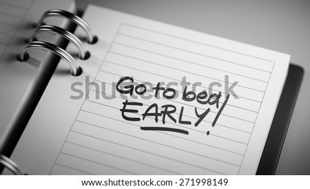 Closeup of a personal agenda setting an important date representing a time schedule. The words Go to bed early written on a white notebook to remind you an important appointment.