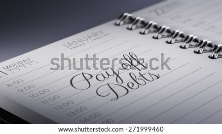 Closeup of a personal calendar setting an important date representing a time schedule. The words Pay off debts written on a white notebook to remind you an important appointment.