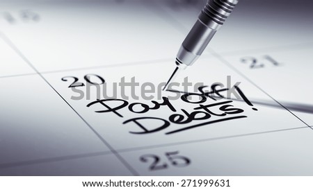 Concept image of a Calendar with a golden dart stick. The words Pay off debts written on a white notebook to remind you an important appointment.