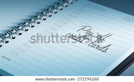 Closeup of a personal calendar setting an important date representing a time schedule. The words Pay off Credit cards written on a white notebook to remind you an important appointment.