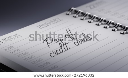 Closeup of a personal calendar setting an important date representing a time schedule. The words Pay off Credit cards written on a white notebook to remind you an important appointment.