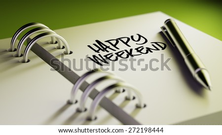Closeup of a personal agenda setting an important date writing with pen. The words Happy Weekend written on a white notebook to remind you an important appointment.
