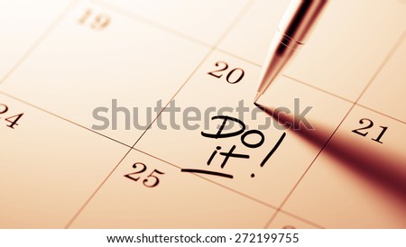 Closeup of a personal agenda setting an important date written with pen. The words Do it written on a white notebook to remind you an important appointment.