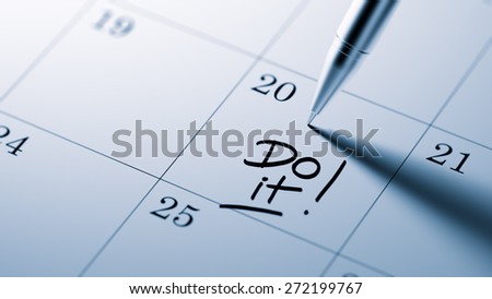 Closeup of a personal agenda setting an important date written with pen. The words Do it written on a white notebook to remind you an important appointment.