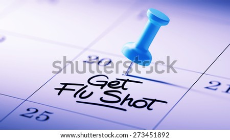 Concept image of a Calendar with a blue push pin. Closeup shot of a thumbtack attached. The words Get Flu Shot written on a white notebook to remind you an important appointment.